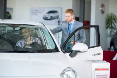 Un vendeur explique les conditions salon de l'auto à un particulier intéressé par l'achat d'un véhicule